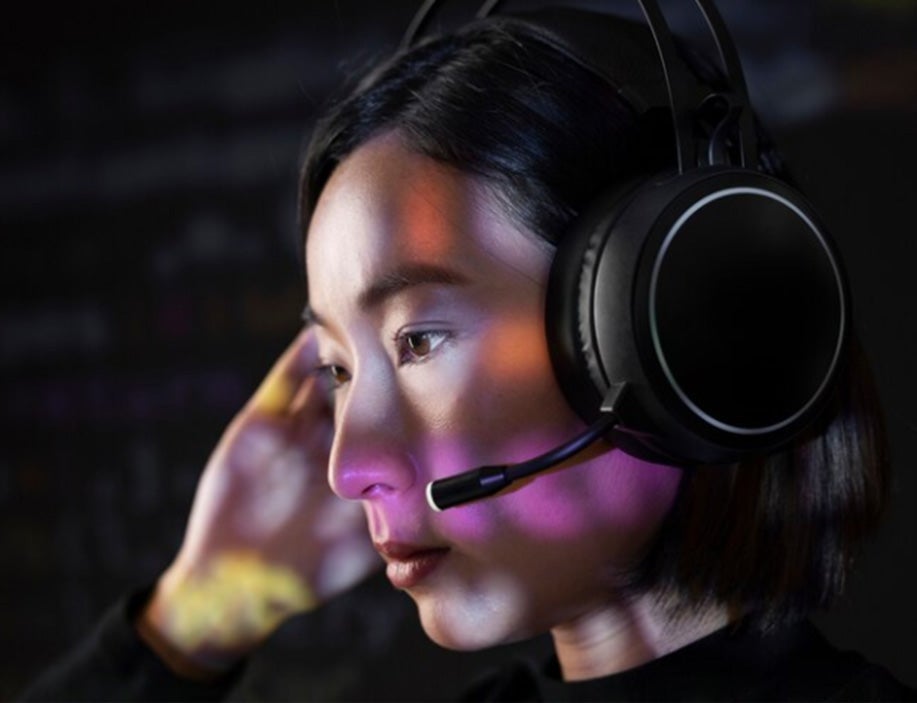 Young woman on computer with headset and bright lights